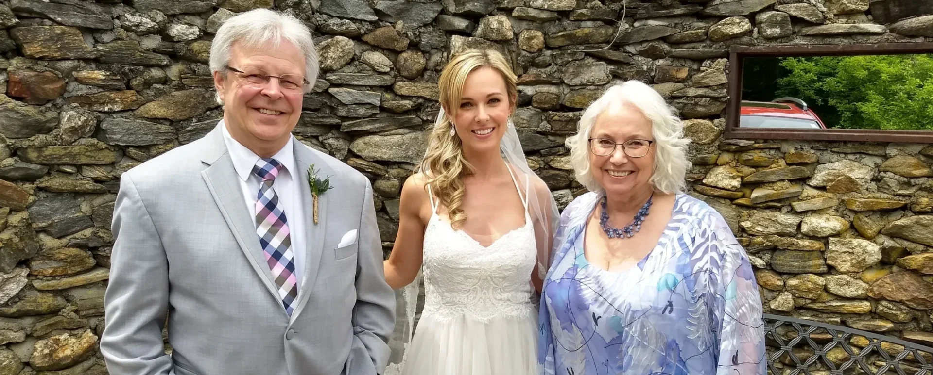 Bride with parents in front of stone wall